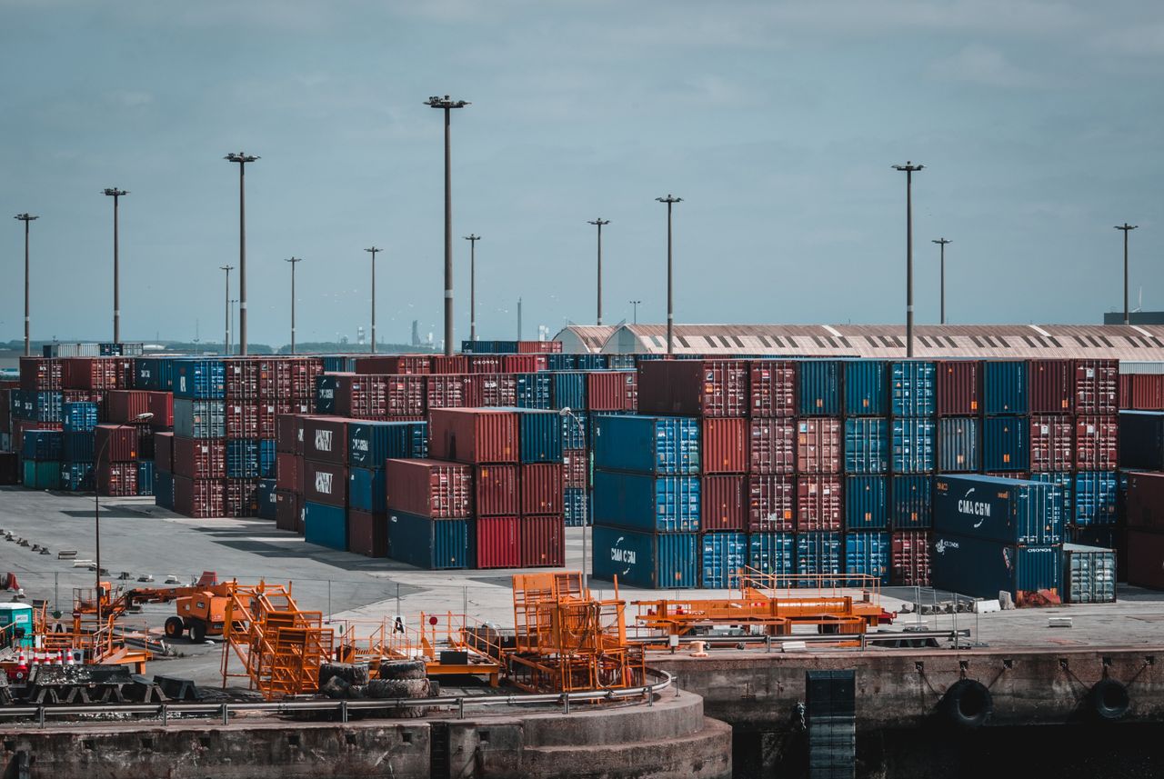 services-01 Colorful cargo containers stacked at a busy industrial port, showcasing global trade.