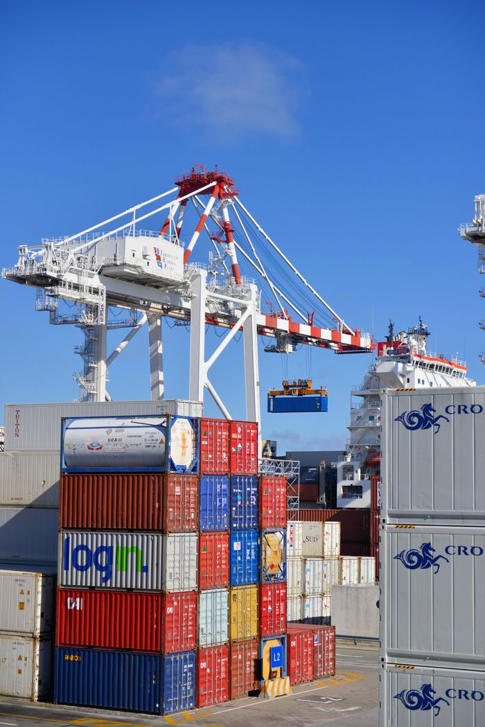 services-02 Colorful shipping containers stacked in a busy port with cranes overhead.